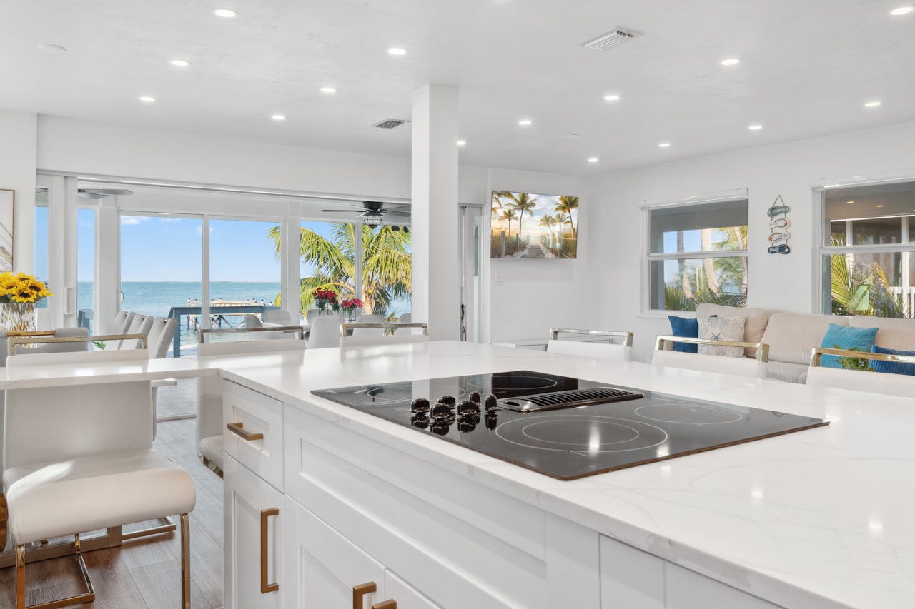 Home Elegant modern kitchen overlooking ocean, featuring sleek appliances and bright decor.